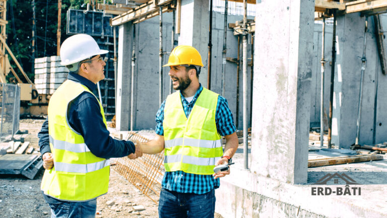 Sur un chantier, deux hommes revêtus de gilets jaunes se saluent en se serrant la main
